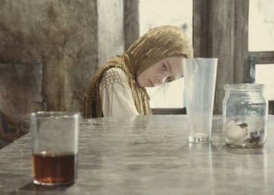 A still from Tarkovksy's Stalker showing a young girl moving a bottle with her mind